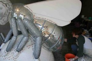Artist decorating Bee sculpture with mirrored tiles